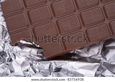 Bitten a piece of chocolate bar in silver foil packaging.