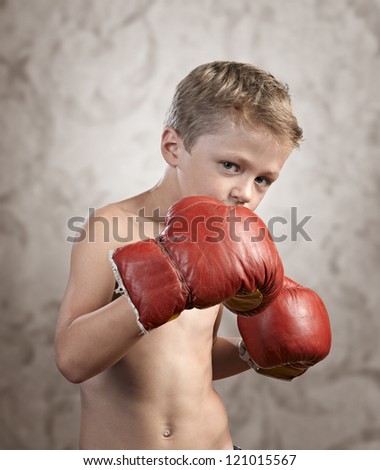 Non Aggressive child wearing boxing gloves on textured background