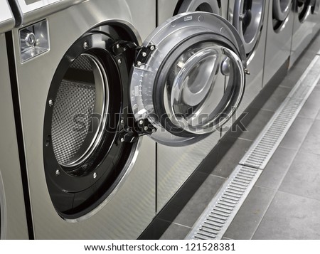 A row of industrial washing machines in a public laundromat