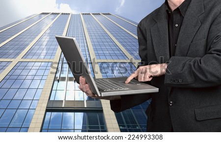 Close up on a businessman with laptop outside modern building
