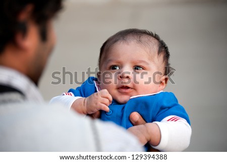 new born baby boy looking at his father in amusement, happy father and son, Indian man holding his new son in arms