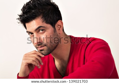 Intense portrait of a man with his hand under the chin, close up of a handsome Indian man