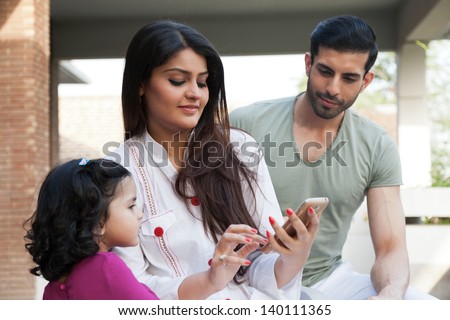 indian or multi ethnic family , mother showing something to her daughter on Phone tablet