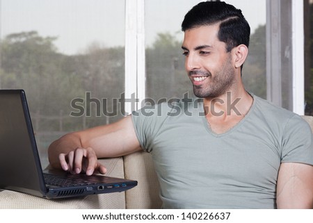 confident man using laptop, happy man sitting on the sofa and using laptop