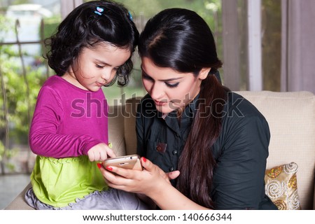 Indian mother and her daughter using smart phone,