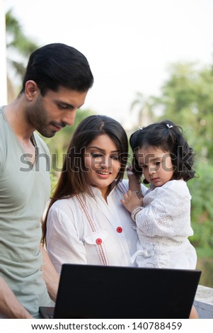 man showing something on the laptop to wife and daughter.