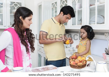 family of three eating fruits in the kitchen, Indian family in the kitchen,