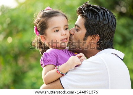 portrait if father kissing daughter in out door against nature background, Indian man kissing his daughter.