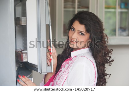 Indian woman opening the door of refrigerator