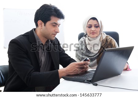 successful muslim business woman in a meeting with her caucasian male colleague; young business couple in an official meeting. business couple working on the laptop