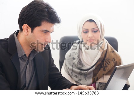 successful muslim business woman in a meeting with her caucasian male colleague; young business couple in an official meeting. business couple working on the laptop