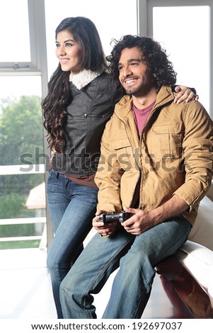 young Indian couple relaxing and playing video games.