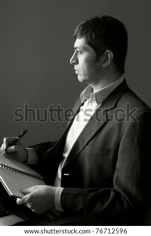 black and white portrait of a mature businessman thinking and writing