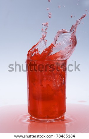 red fruity juice water splash coming out of a glass