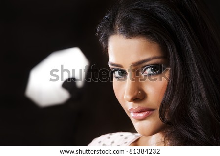 Attractive Indian girl with beautiful long hair, female fashion model posing for the camera against the umbrella light in background