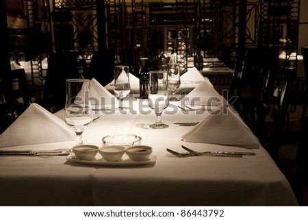 dining setup with wine glasses silver cutlery  and white napkins in a modern restaurant