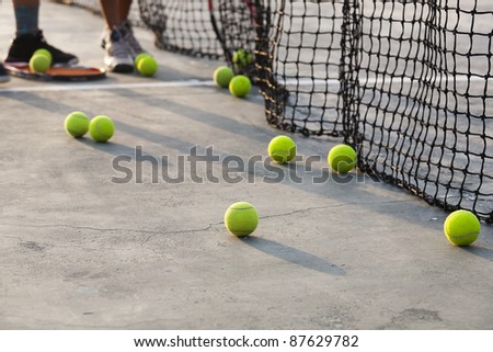group of tennis balls, boy collecting tennis balls from the court after practice session.