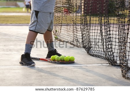 group of tennis balls, boy collecting tennis balls from the court after practice session.