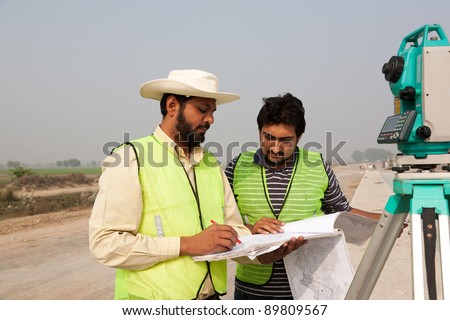 two civil engineers doing a survey on a construction site. engineers doing land survey on site.