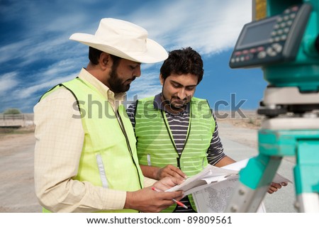 two civil engineers doing a survey on a construction site. engineers doing land survey on site.