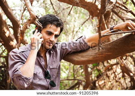 remote connectivity, man standing in the jungle and talking on mobile phone