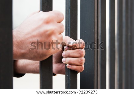 woman holding the hands of her husband behind the bars