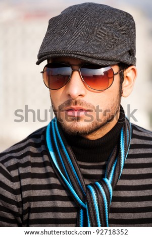 portrait of a handsome and confident man wearing sweater and cap in outdoor, handsome man wearing sunglasses