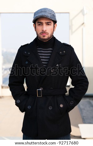 Portrait of a biracial man wearing over coat, portrait of a handsome and confident young man wearing a muffler and over coat with a cap