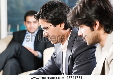 confident indian businessman with his colleagues in the background