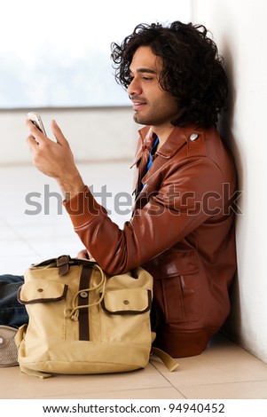 male university student sitting alone corridor,man sending or reading sms