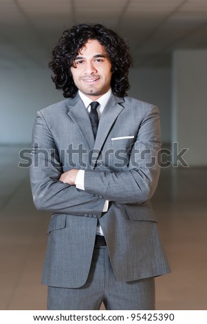 mixed race businessman standing in the office hall, portrait of a businessman with copy space.