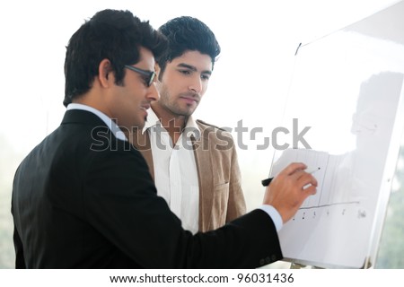two young businessmen discussing business strategy in a meeting, Indian business man with latin american colleague, two serious businessmen,