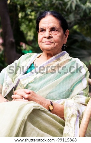 portrait of a graceful senior indian woman, senior Indian woman sitting in the lawn or garden