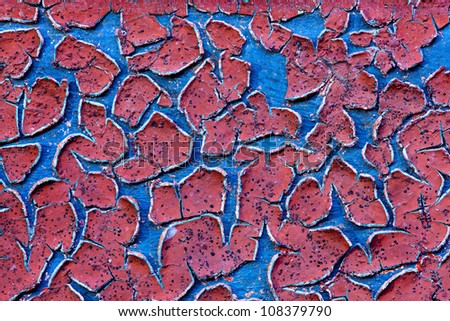 Grunge wall texture background. Red paint cracking off the wall with blue paint underneath.