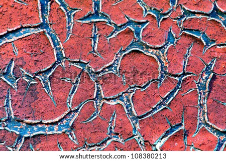 Grunge wall texture background. Red paint cracking off the wall with blue paint underneath.