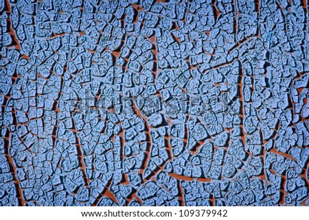 Grunge wall texture background. Blue paint cracking off the wall with red paint underneath.