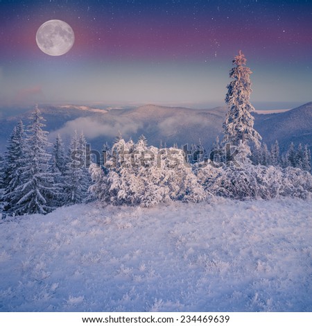 Rising moon over frosty winter mountains.