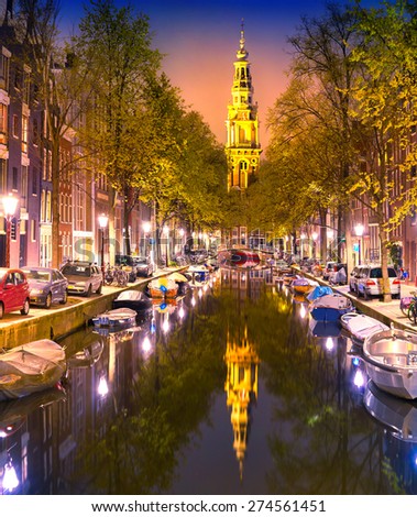 South Church Zuiderkerk and Amsterdam Canals at dusk. Night time illuminations of buildings with reflections on water. Netherland, Europe.