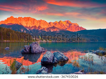 Colorful summer scene on the Eibsee lake in German Alps. Germany\'s highest mountain Zugspitze 2 962 m, and it\'s mountain ridge painted in red of the last rays of sunset. Germany, Europe.