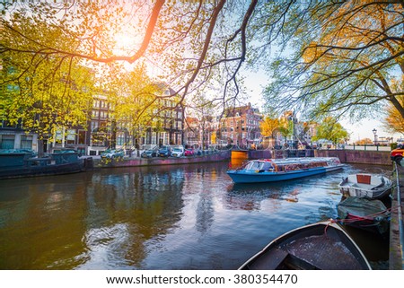 Spring scene in Amsterdam city. Tours by boat on the famous Dutch canals. Colorful evening landscape in Netherlands, Europe.