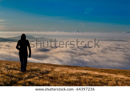 silhouette of the man walking above the clouds