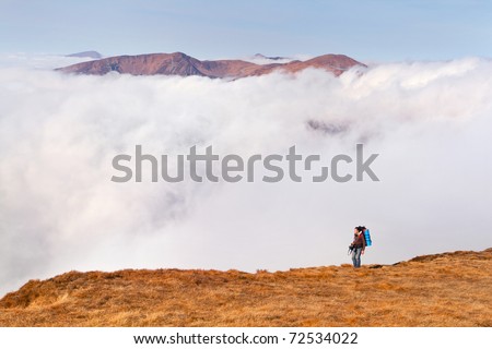 A man with a backpack is on the edge of cliffs in the mountains