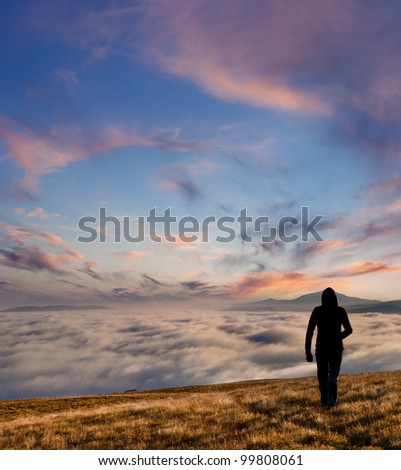 silhouette of the man walking above the clouds on the sunrise