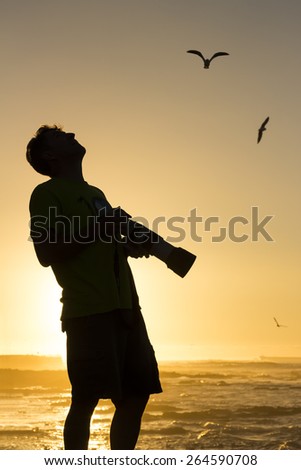 Photographer gazing skyward to photograph birds at sunset