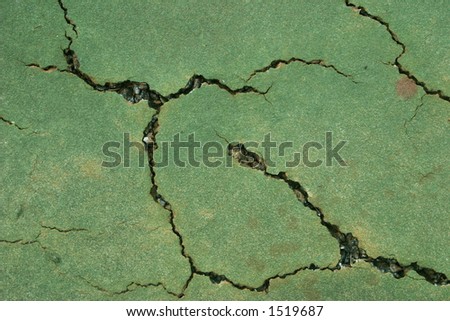 Close up view of a cracked tennis court surface in need of repair.