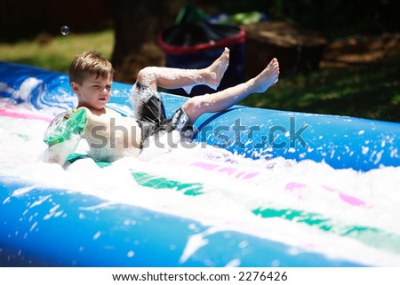 Young boy sliding down a water slide
