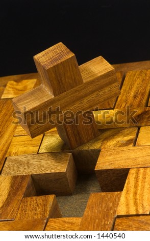 A cross of wood trying to go to its place in the wooden puzzle