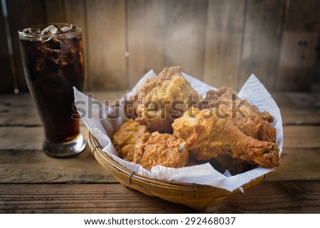 Fried Chicken with slightly smoke in a basket on a wooden floor.