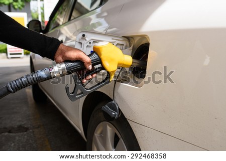 Hand refilling the car with fuel, focus hand