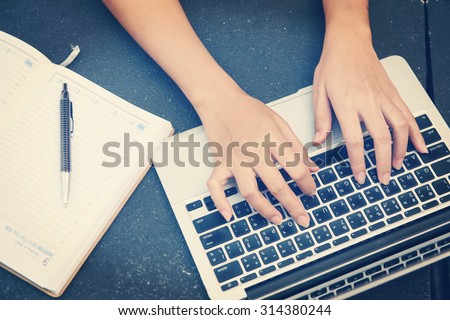 Woman working on laptop and writing, top view